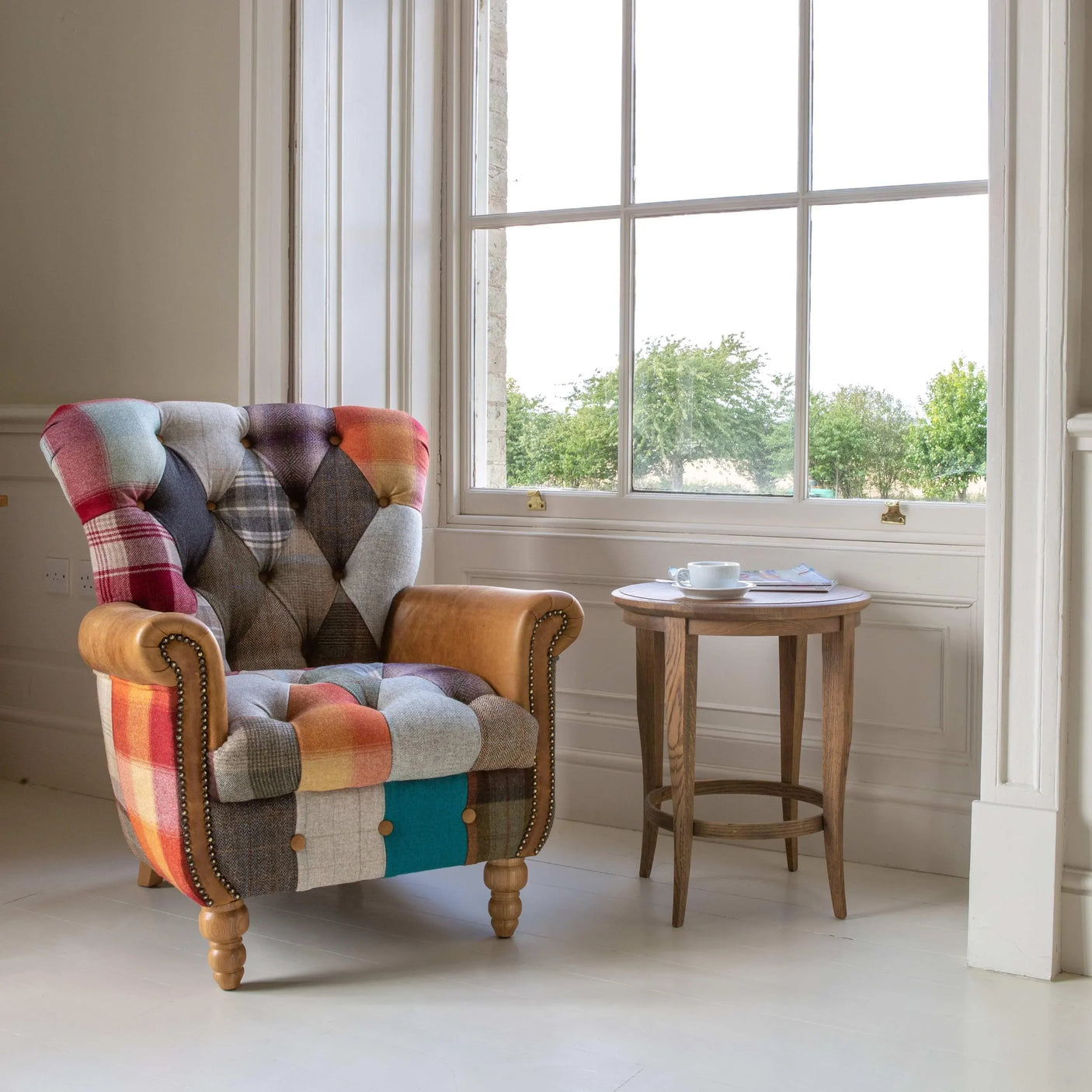 Patchwork fabric armchair with wooden legs beside round oak side table in bright living room