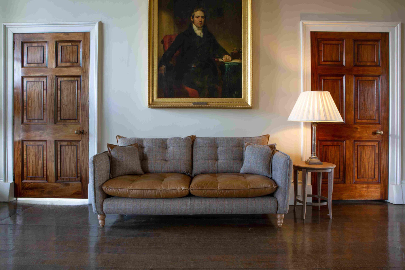Leather and tweed three-seater sofa with cushions, side table and lamp in classic living room
