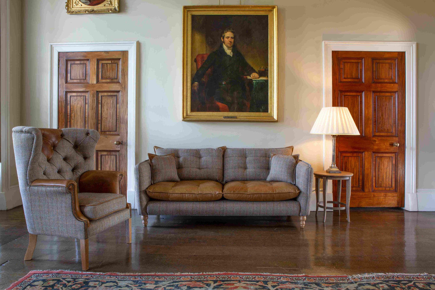 Plaid fabric sofa with leather seat cushions and matching armchair in classic living room