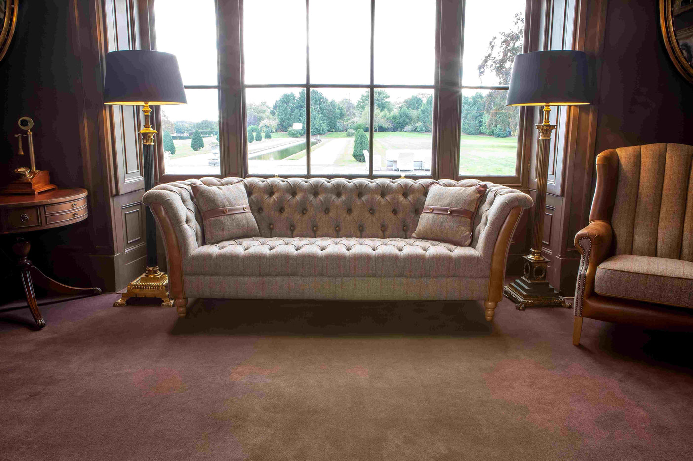 Grey tufted fabric sofa with two cushions in classic living room with large window