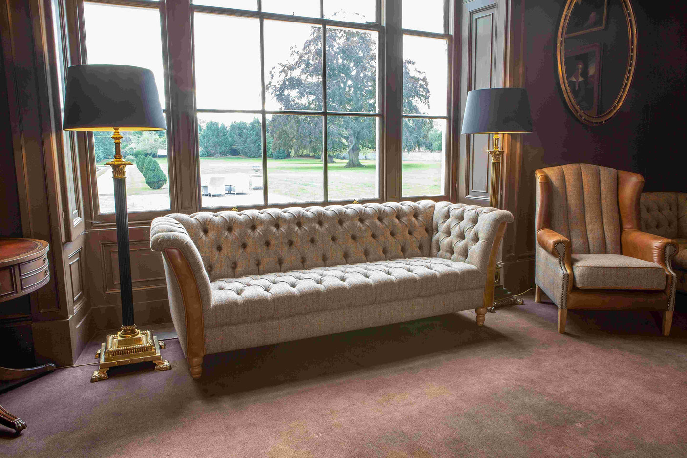 Chesterfield sofa with tufted grey upholstery and wooden legs in classic living room setting