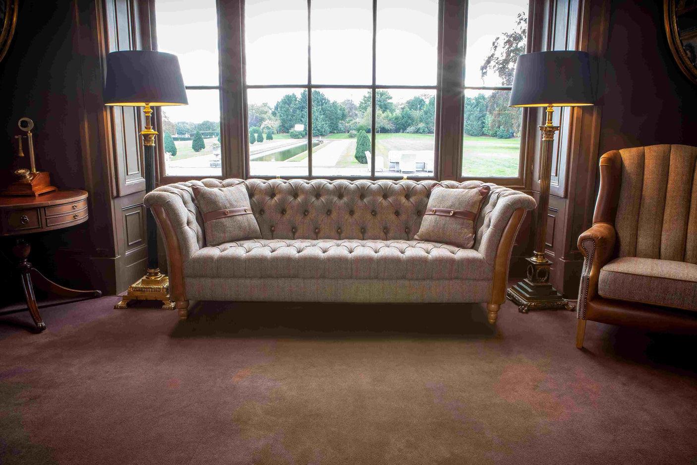Grey tufted fabric sofa with matching cushions in a living room with large windows