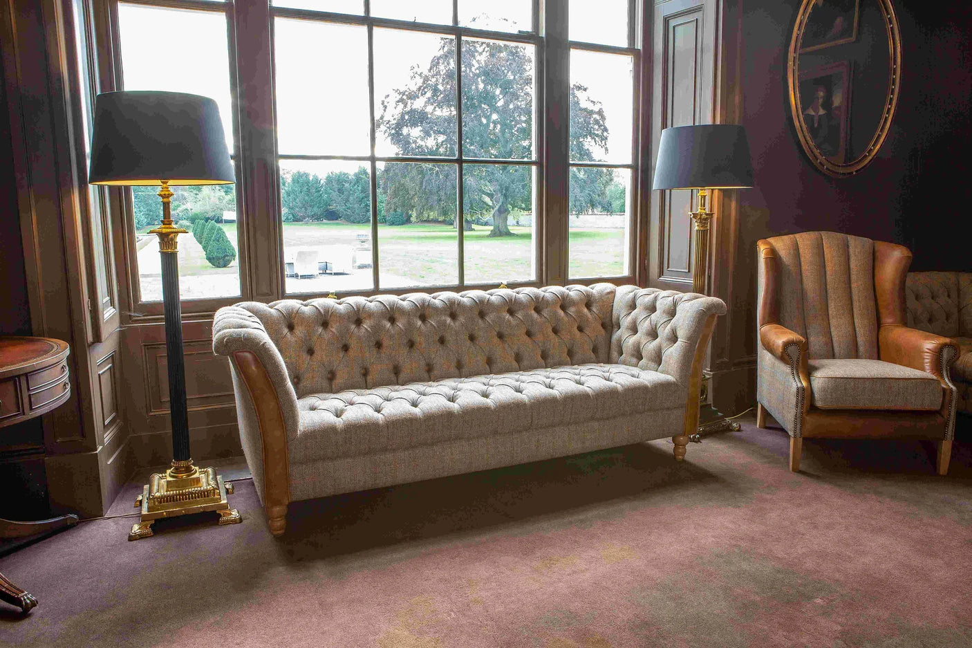 Chesterfield sofa in tufted grey fabric with brown leather arms in classic living room setting