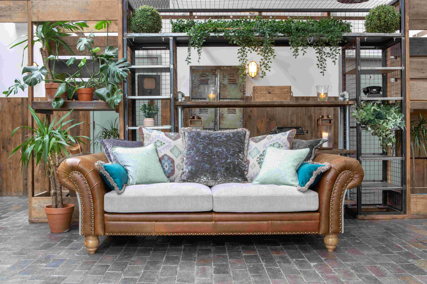 Brown leather sofa with light fabric seat and decorative cushions in a rustic indoor setting