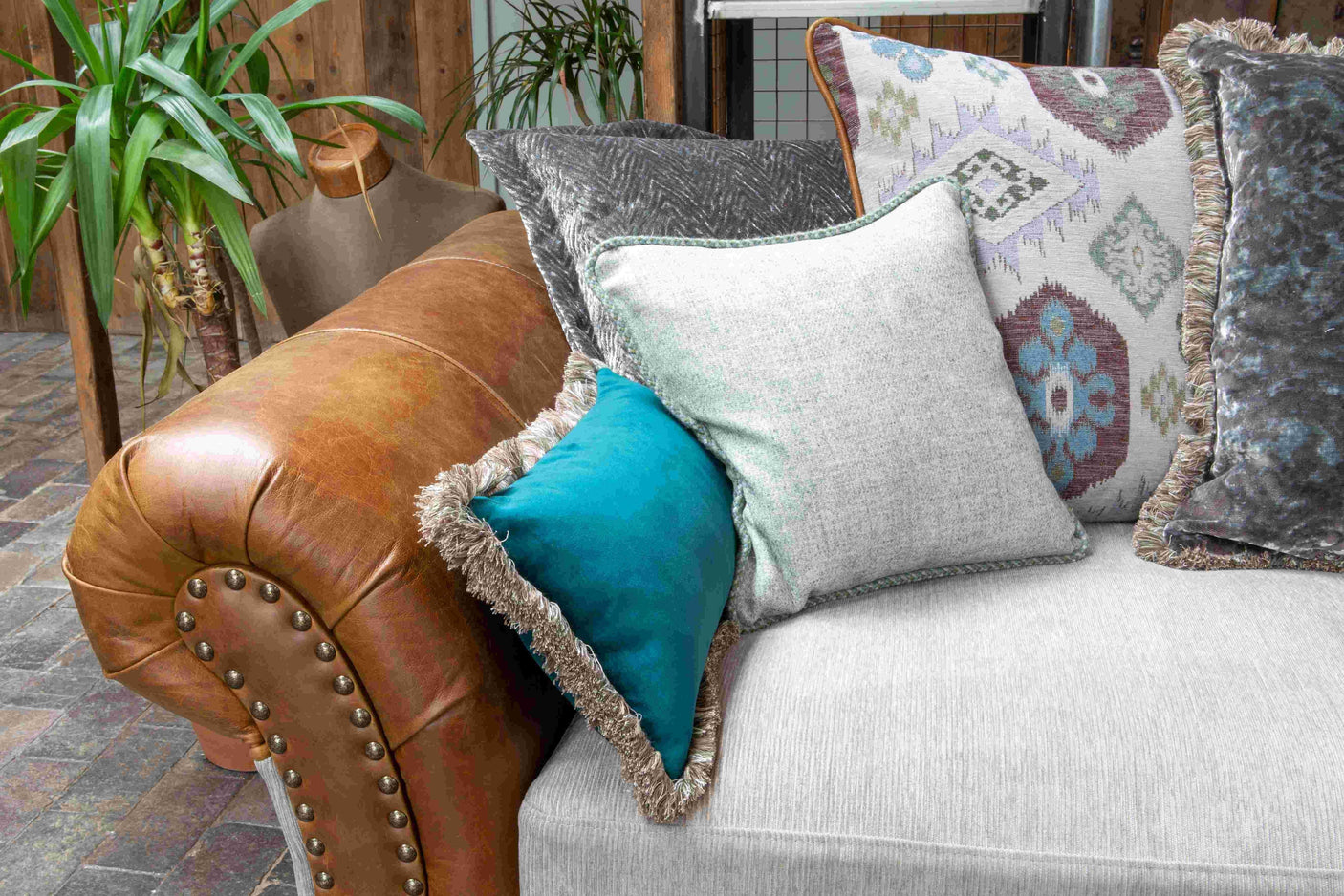 Brown leather arm sofa with grey seat and assorted patterned scatter cushions