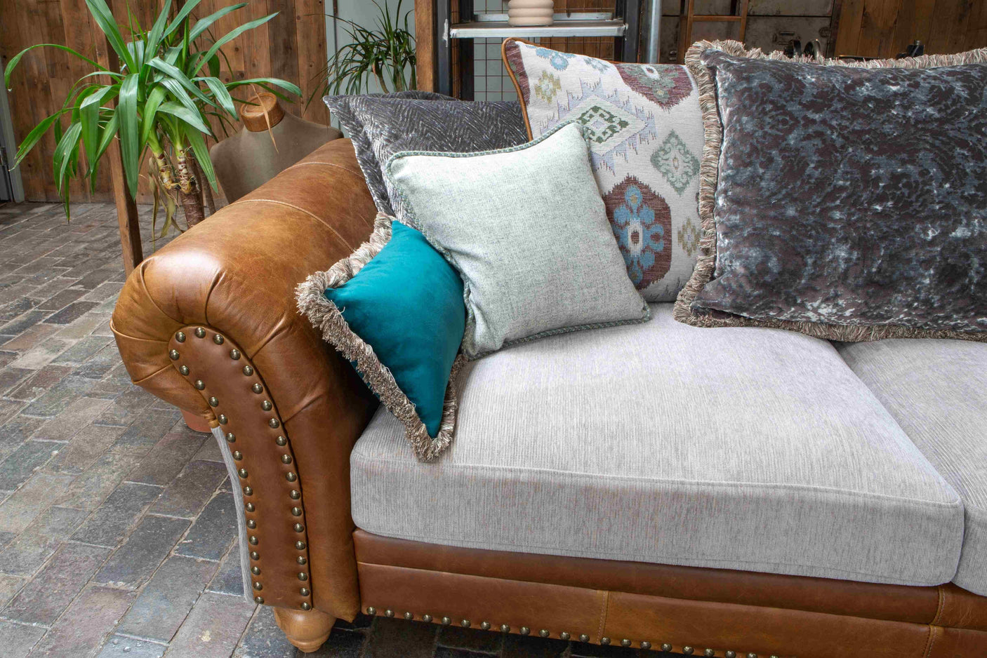 Brown leather and fabric sofa with studded arm and assorted patterned cushions