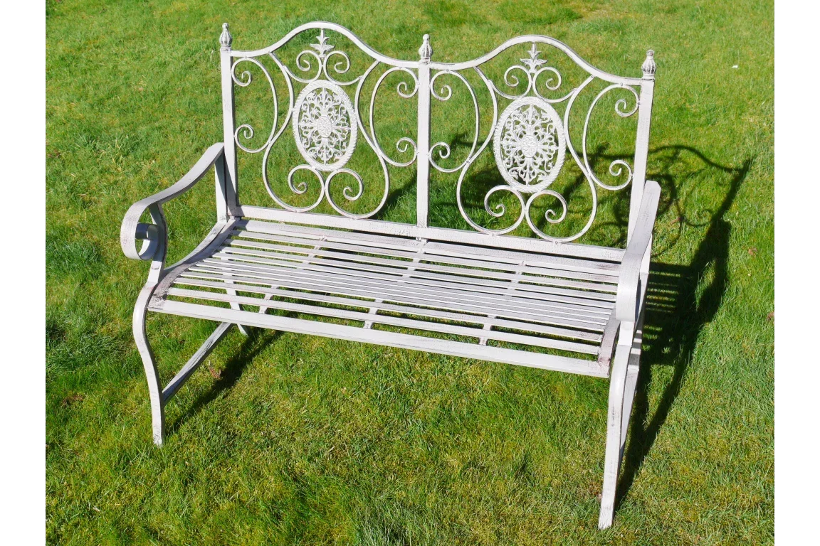 Ornate metal garden bench with decorative scrollwork on green lawn