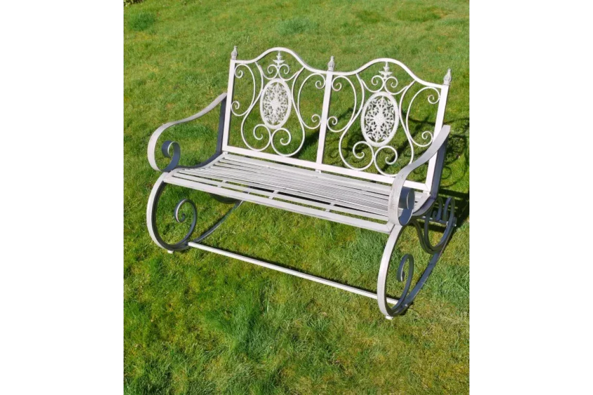 ornate metal garden bench with scroll armrests on green lawn