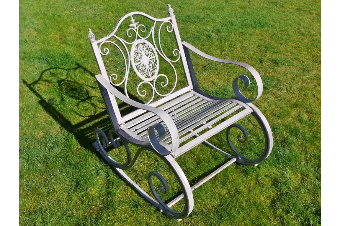Decorative metal garden rocking chair with ornate scrollwork on grass lawn