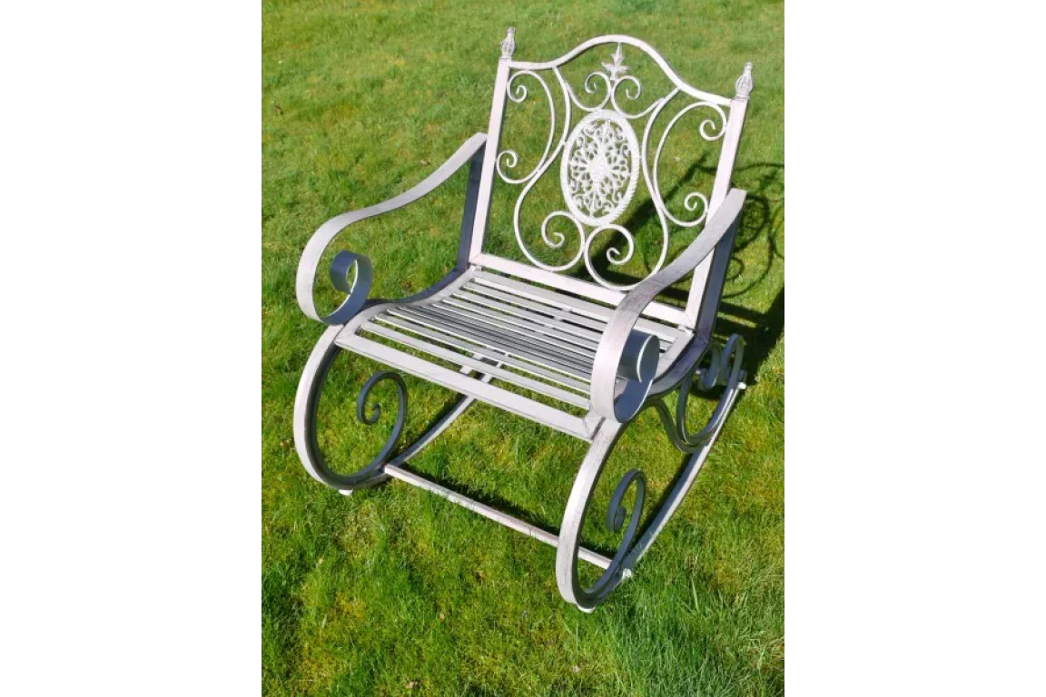 Metal garden rocking chair with ornate scrollwork design on grass