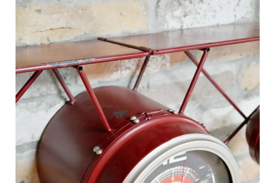 Red metal wall clock with shelf, industrial style against exposed brick background