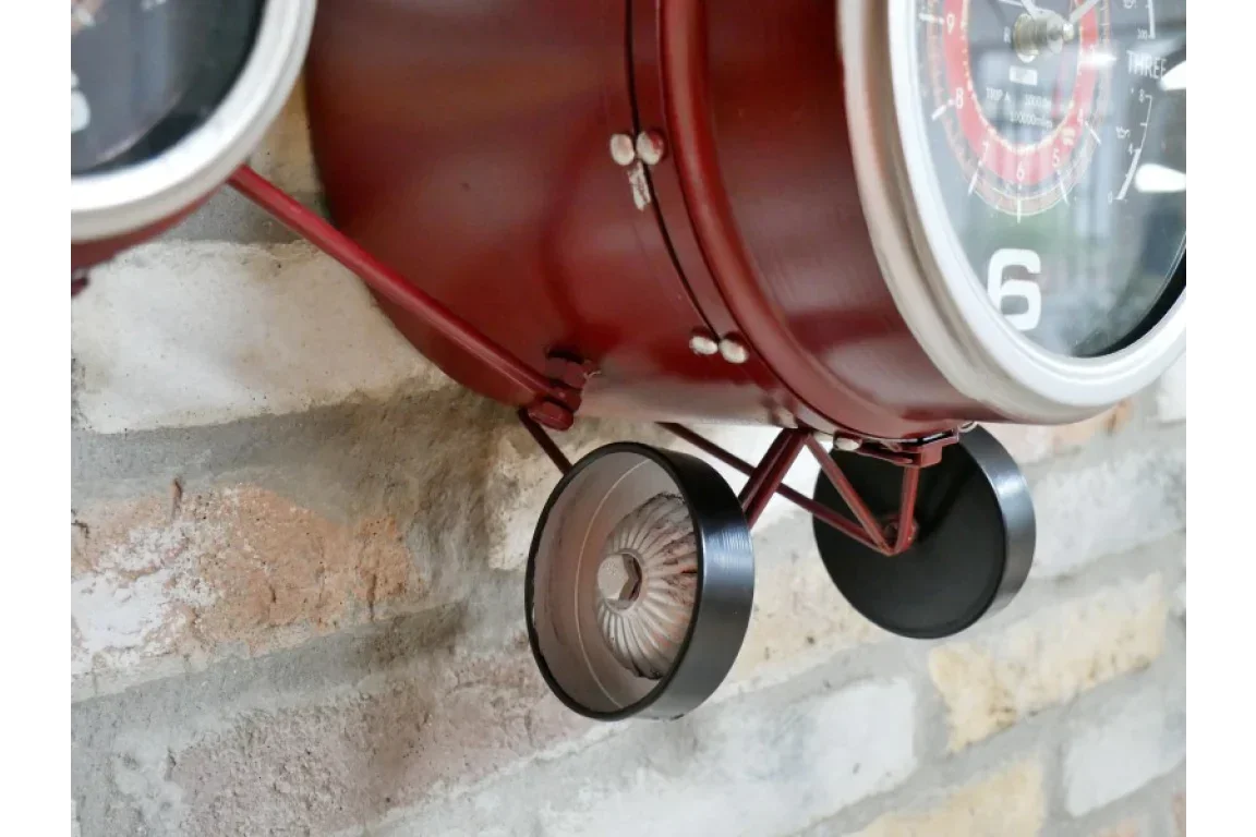 Red vintage wall clock with metal wheels, close-up on aircraft-inspired design details