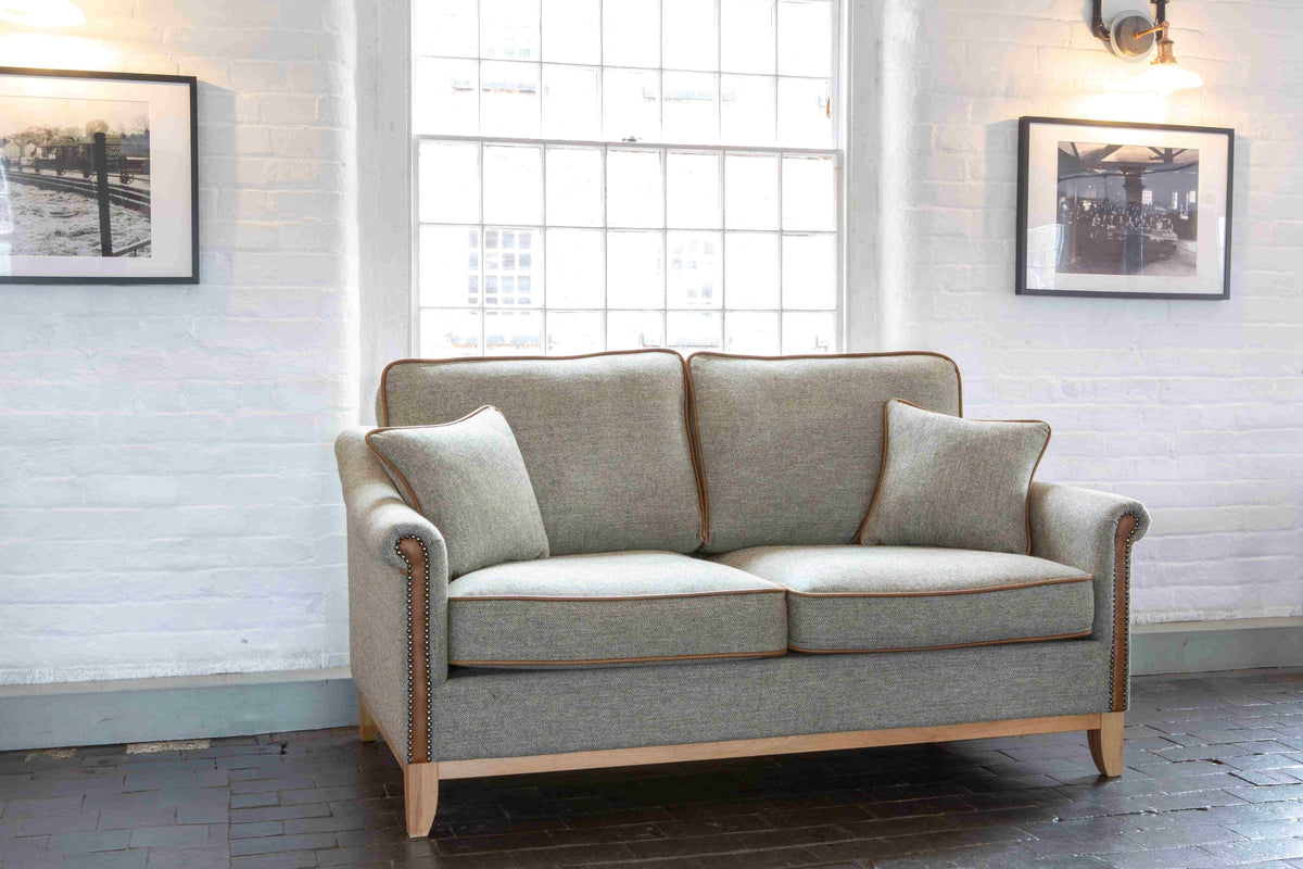 Grey fabric sofa with wooden legs and studded arms in bright living room