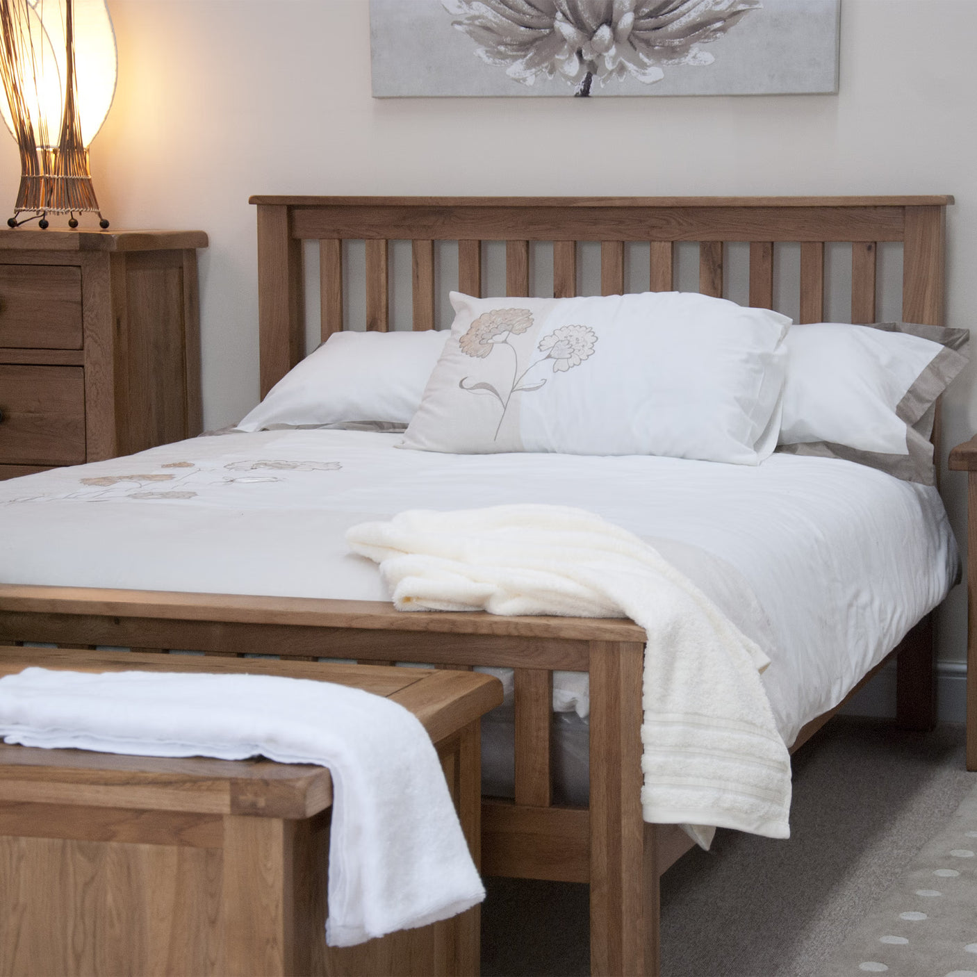 Wooden bed frame with white bedding and matching bedside cabinet in cosy bedroom setting