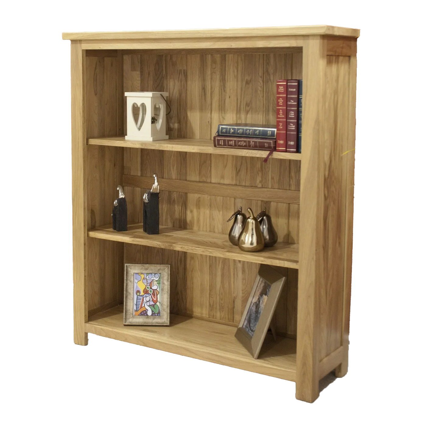 Oak bookcase with three shelves holding books, metallic ornaments, and framed photos