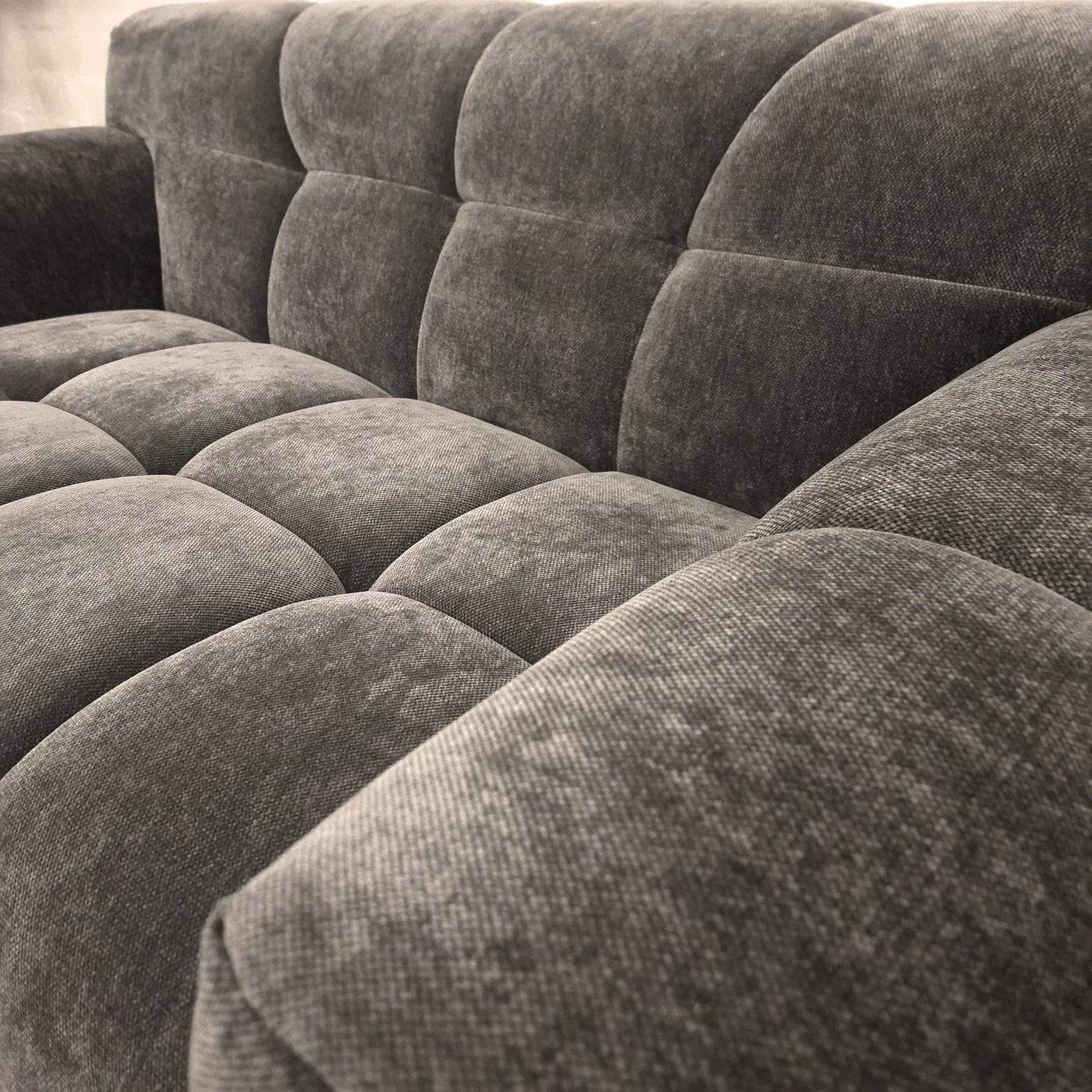 Grey fabric sofa with tufted seat and backrest, close-up of upholstery texture