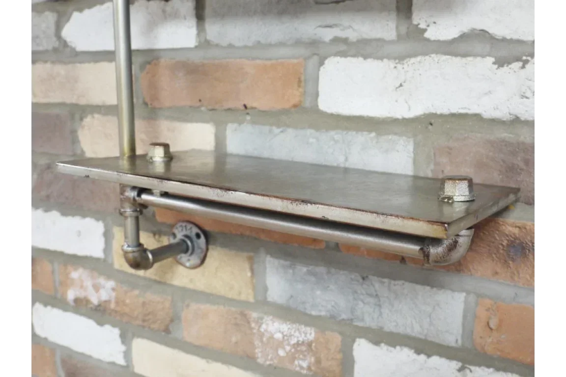 Industrial metal wall shelf with pipe brackets mounted on exposed brick wall