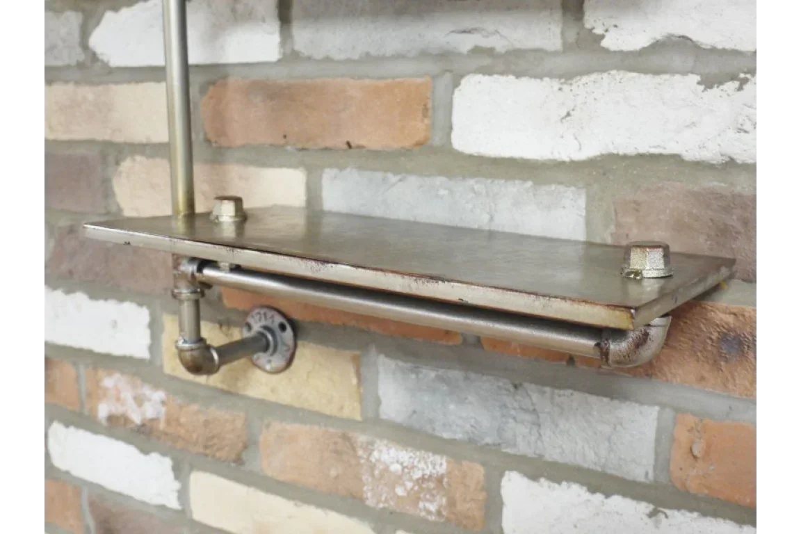 Industrial metal wall shelf with pipe brackets mounted on exposed brick wall