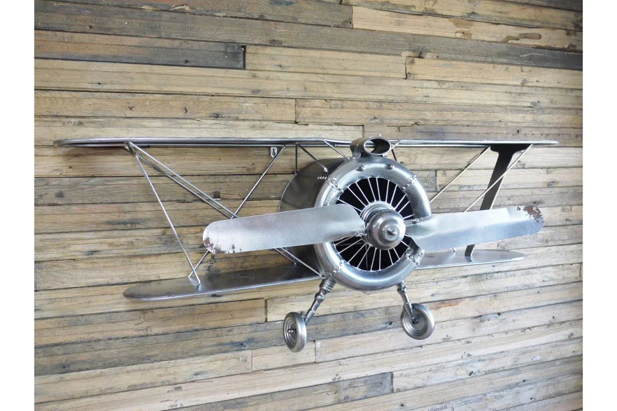 Metal airplane wall art with propeller mounted on rustic wooden wall