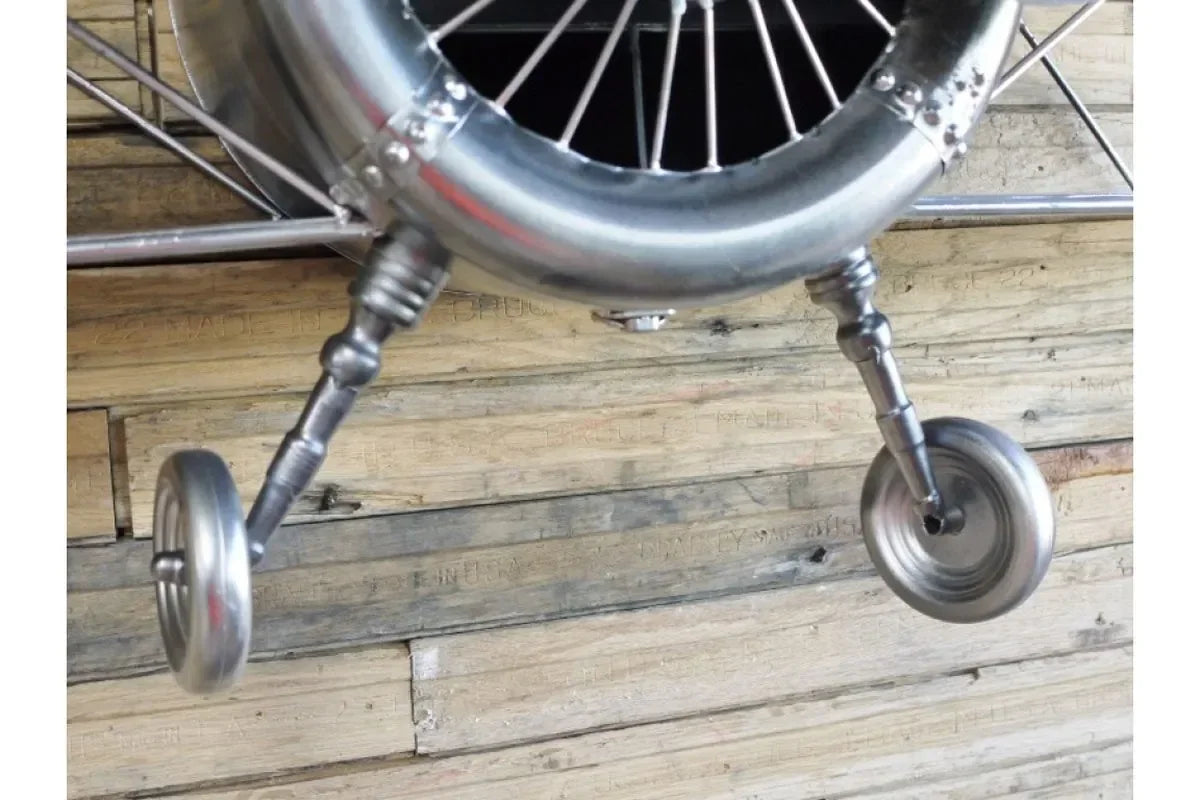Silver metal model airplane wheels and landing gear on wooden floor