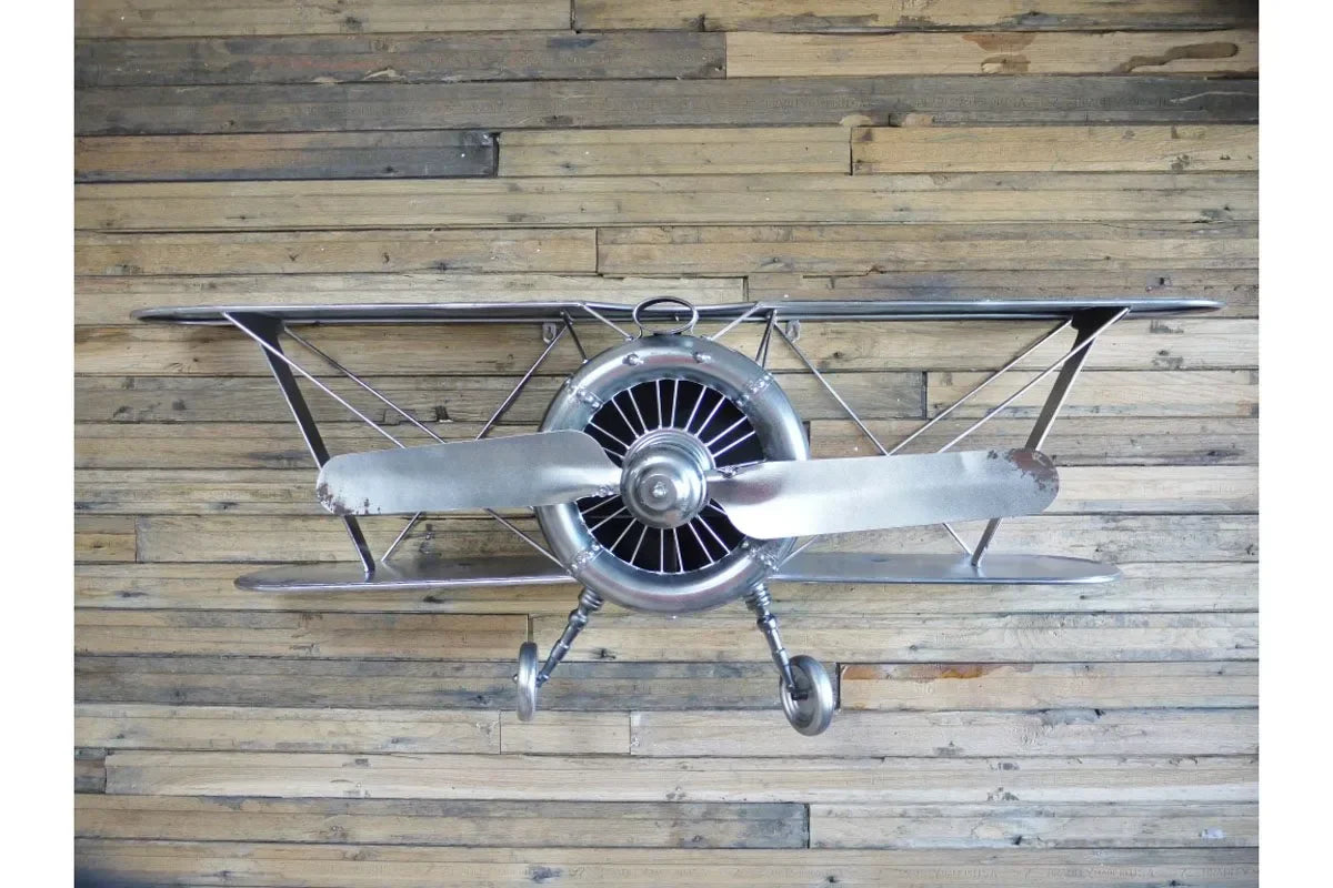 Metal biplane wall art with propeller mounted on reclaimed wooden plank background