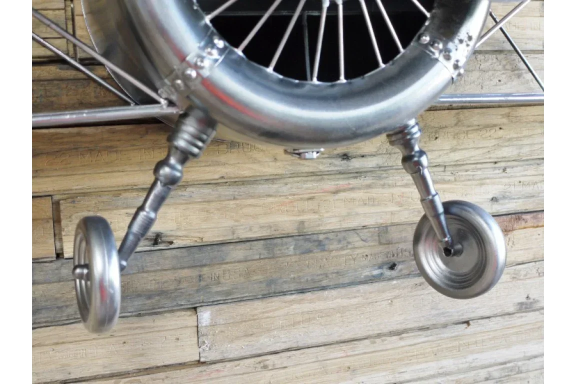 Closeup of metal airplane decor landing gear with wheel detail on rustic wood floor
