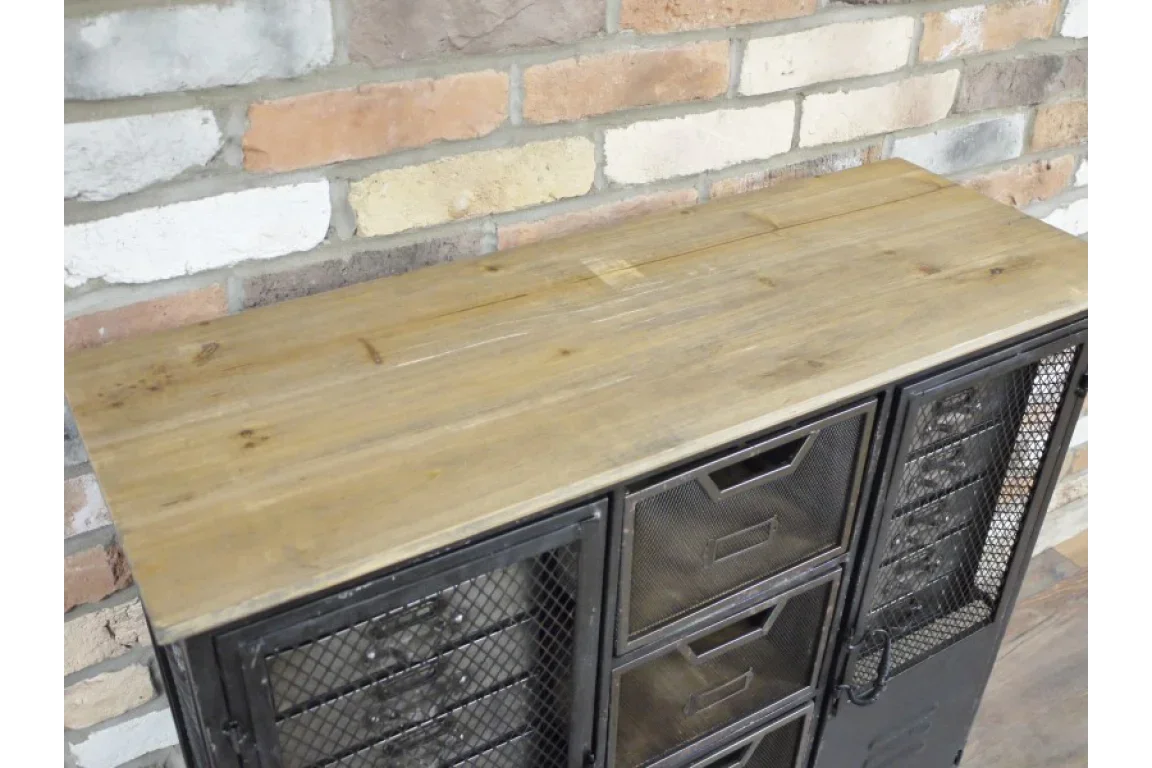 Industrial storage cabinet with metal mesh drawers and reclaimed wood top against brick wall