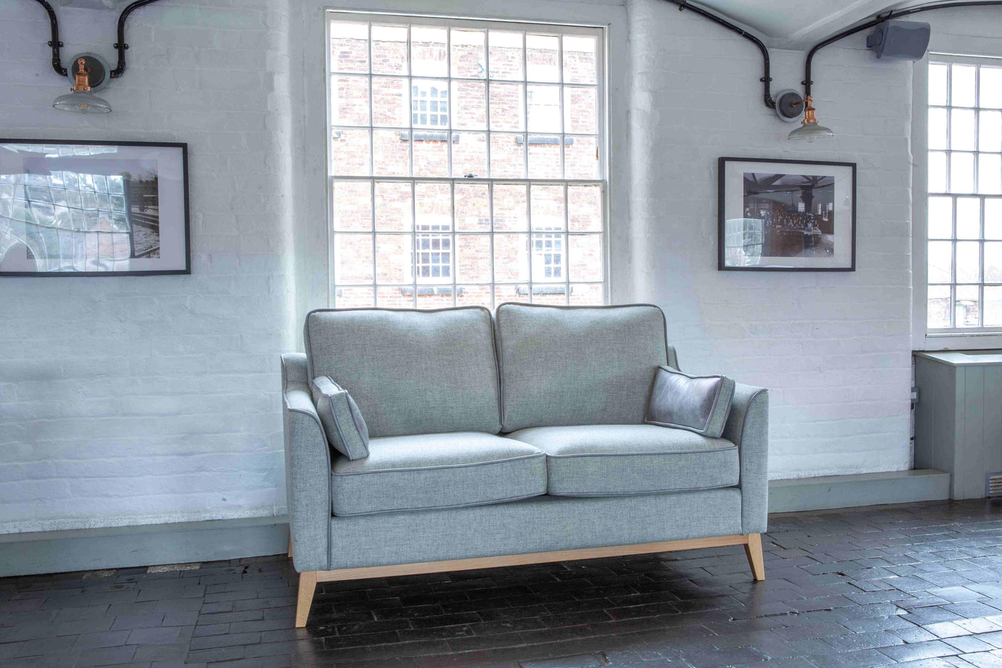 Light grey fabric sofa with wooden legs and cushions in a bright living room setting