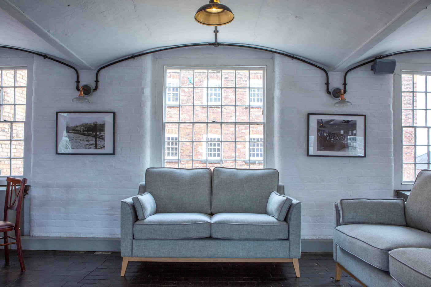 Light grey fabric sofa with wooden legs in a modern living room with large windows