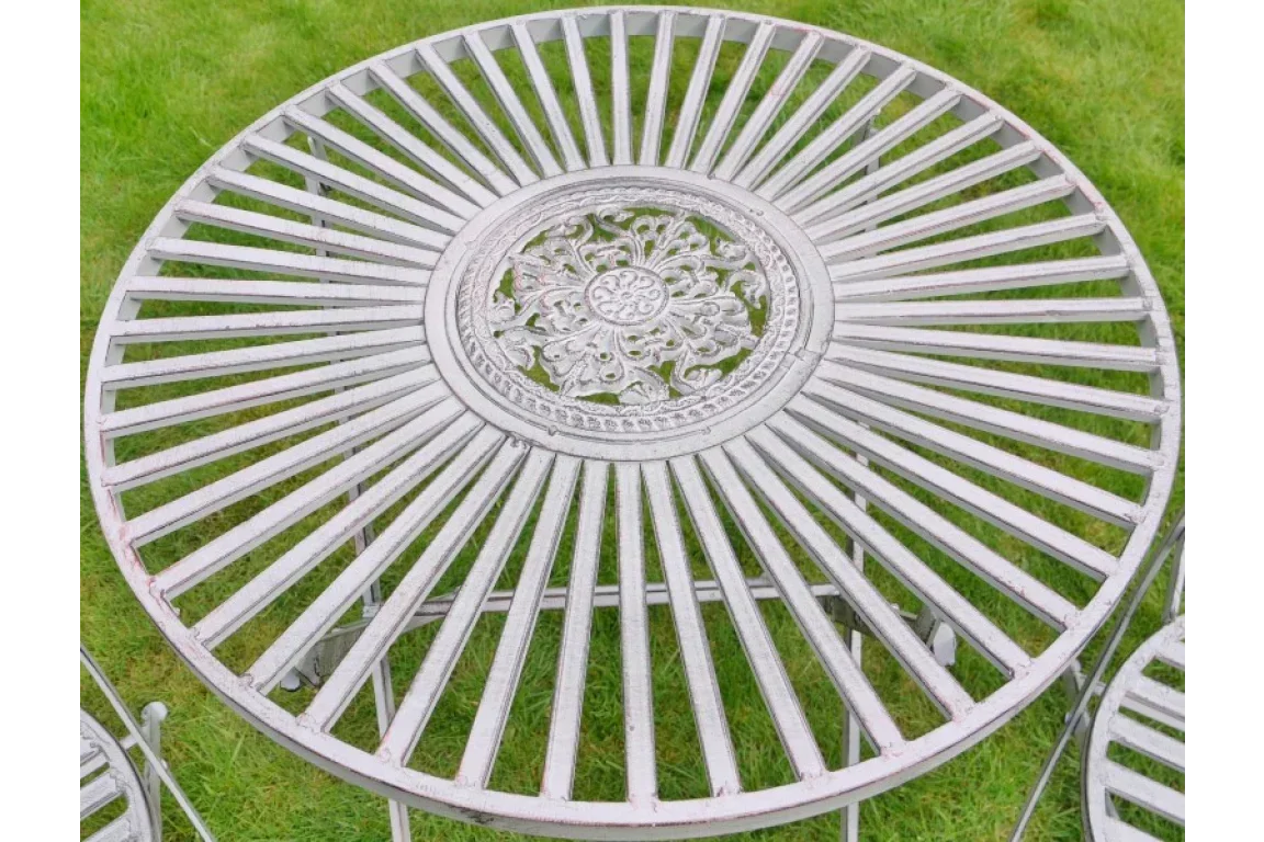 Round metal garden table with decorative floral pattern and slatted top on grass