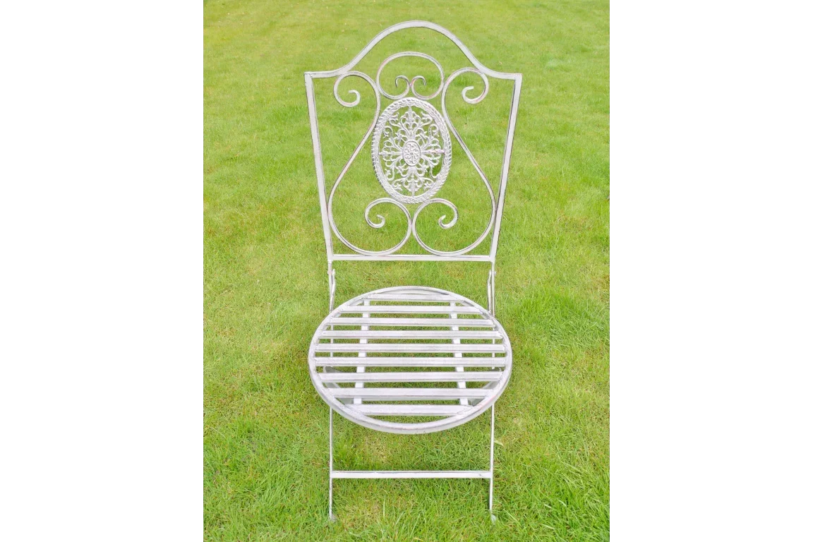 Metal garden chair with ornate scroll backrest and slatted round seat on grass