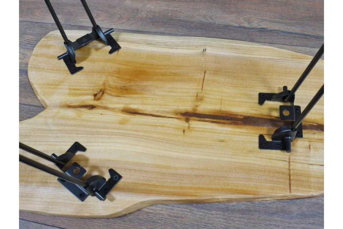 Live edge wooden coffee table top with black metal hairpin legs on wood floor