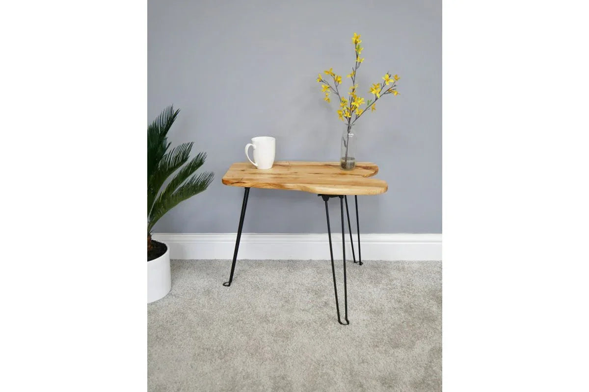 Wood side table with black metal hairpin legs, mug and vase on top, indoor setting