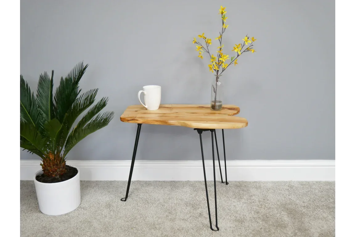 Live edge wooden side table with black hairpin legs, cup and vase, next to a potted plant