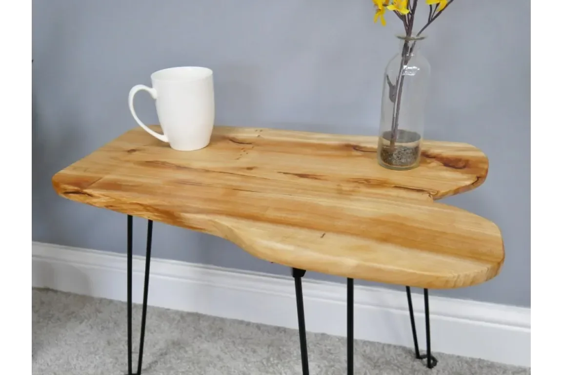 Live edge wooden side table with metal hairpin legs, cup and glass vase with yellow flowers