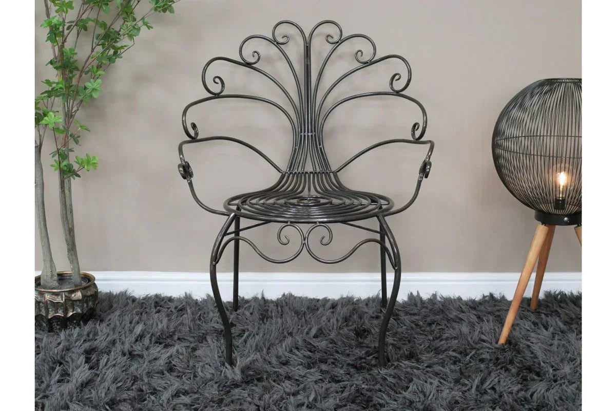 Black metal accent chair with curved frame and swirled backrest on grey rug