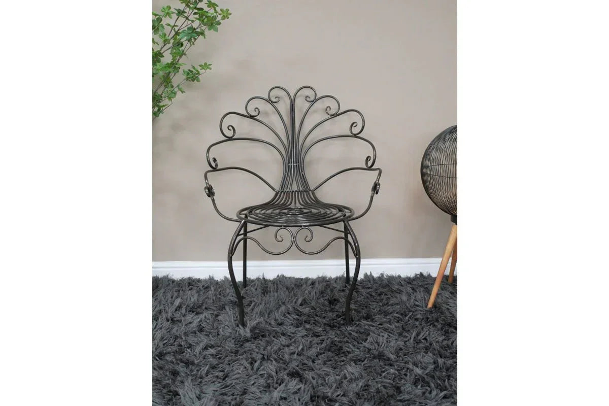Black metal accent chair with ornate scroll design on a grey shaggy rug