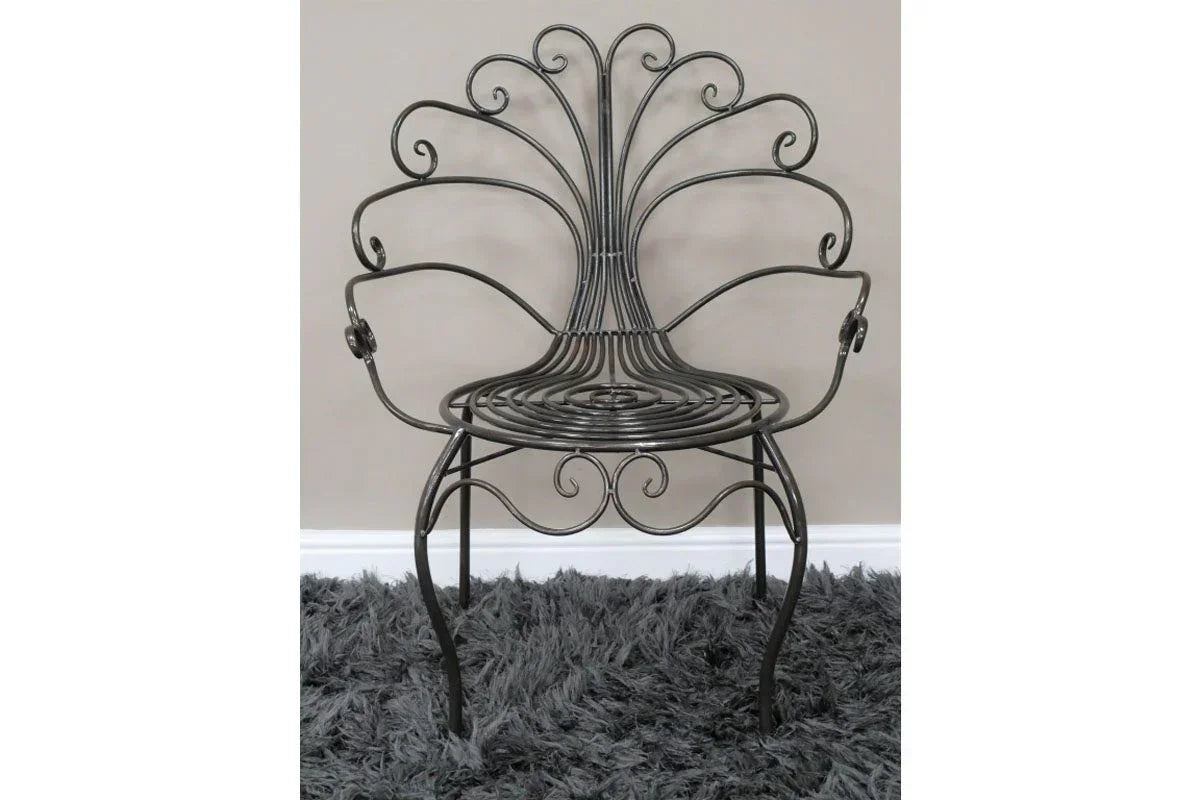 Black metal accent chair with ornate scrollwork backrest and round seat on grey rug