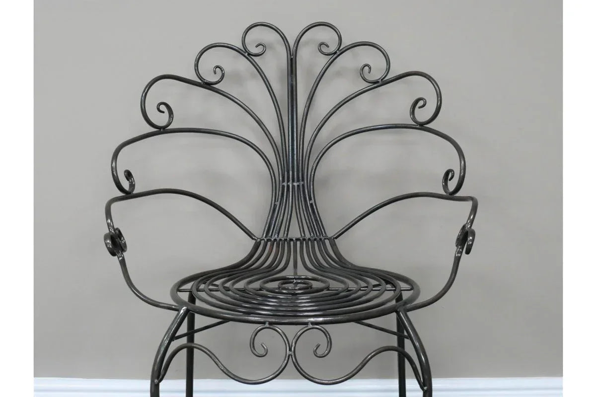 Black metal accent chair with decorative scrollwork and curved arms against grey wall
