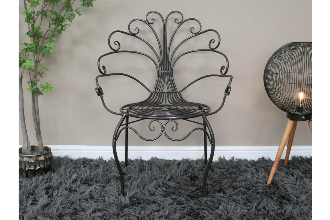 Black metal accent chair with ornate scrollwork design on a grey shaggy rug