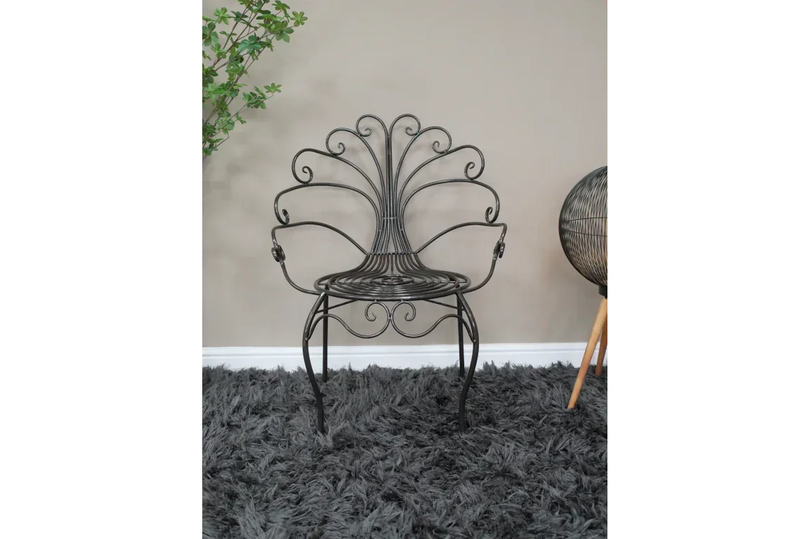 Black metal accent chair with ornate scroll design on grey shaggy rug