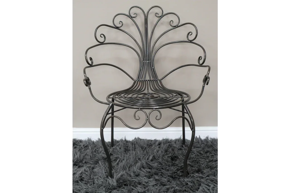 Black metal accent chair with ornate scrollwork design on a grey shaggy rug