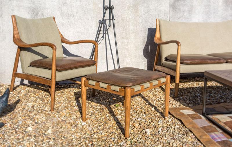 Outdoor wooden armchair and ottoman set with brown leather cushions on gravel patio