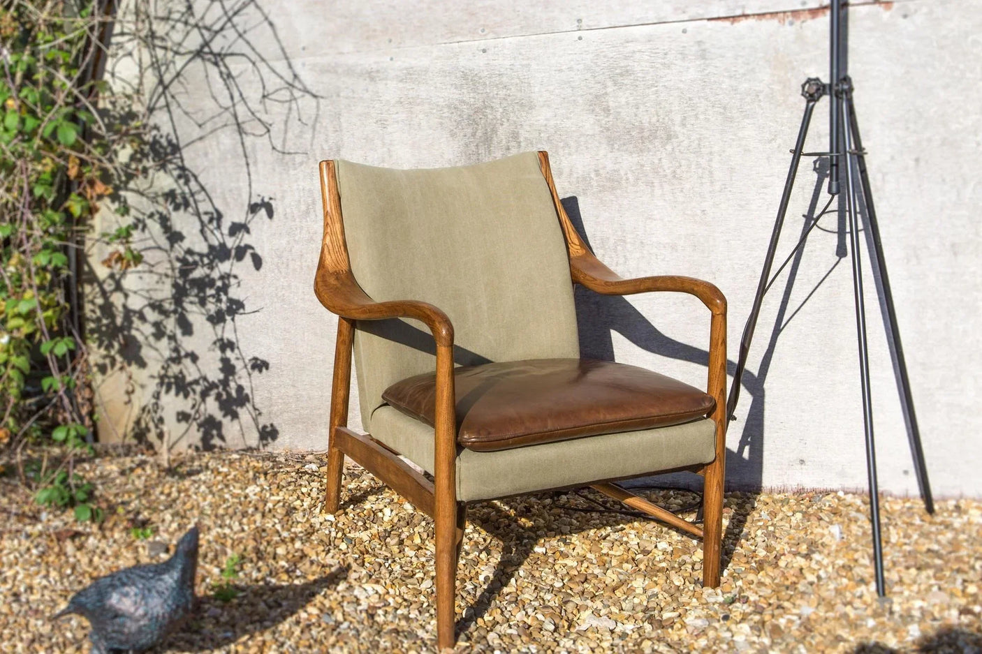 Wood frame accent chair with olive green upholstered back and brown leather seat outdoors