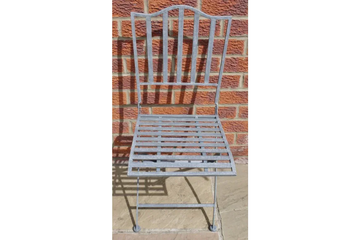 Metal garden chair with slatted seat and backrest against brick wall