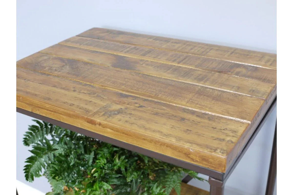 Rustic wood console table with slatted top and metal frame, displayed above green foliage