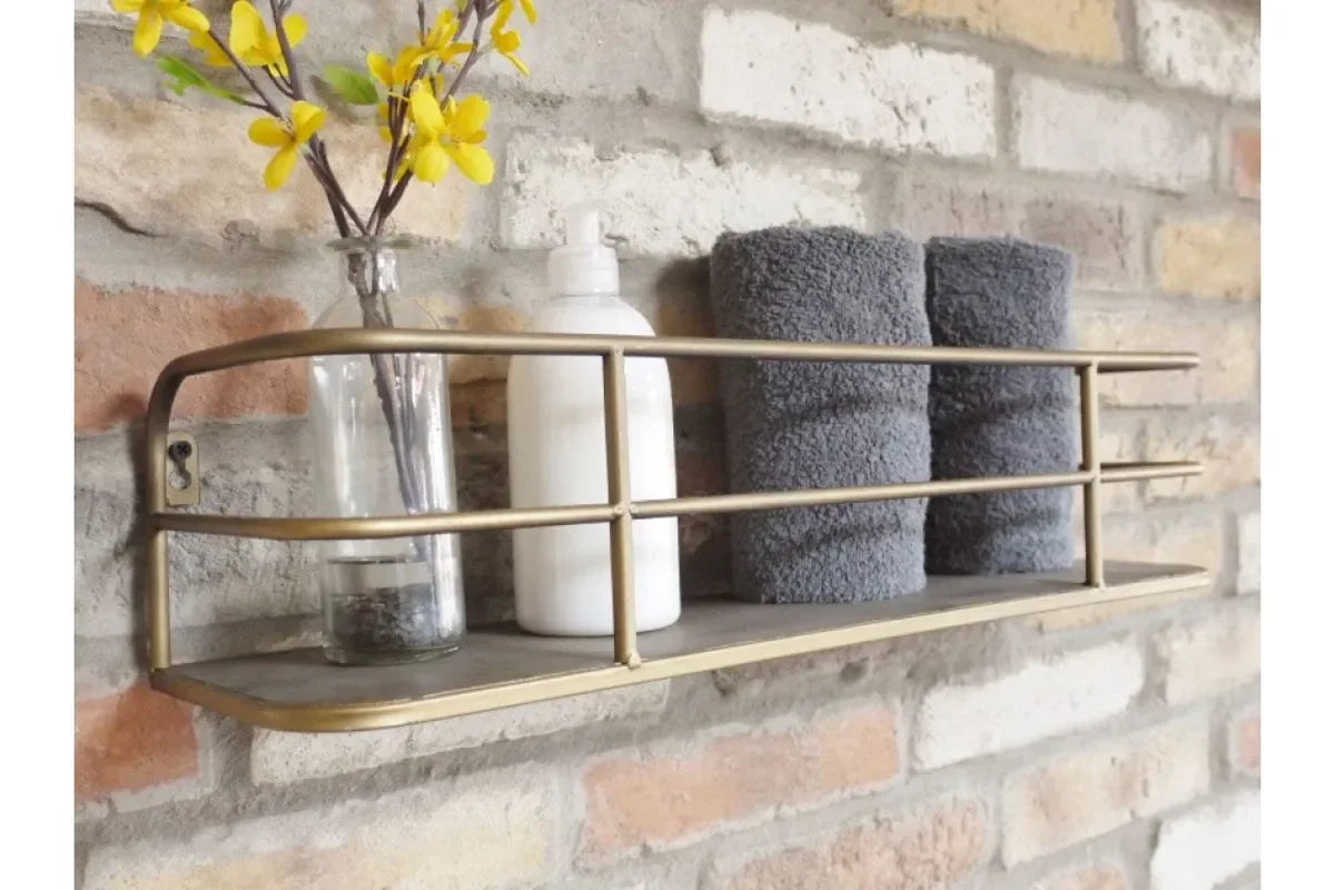 Wall mounted metal shelf with rolled grey towels, bottle, and vase against brick wall