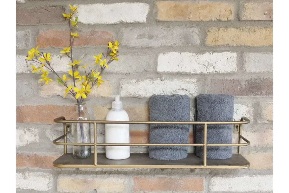 Metal wall shelf with vase, yellow flowers, white soap dispenser and grey towels on brick wall