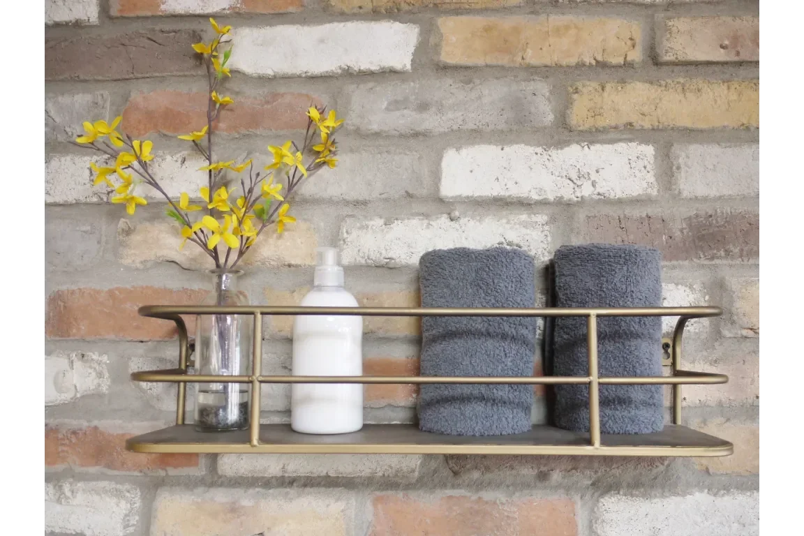 brass bathroom wall shelf with rolled grey towels, soap dispenser, and yellow flower vase