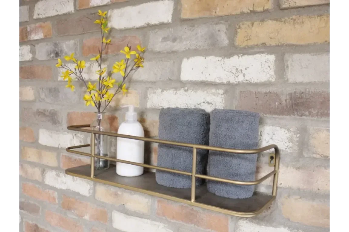 Wall mounted shelf with metal frame holding grey towels, lotion pump, glass vase with yellow flowers